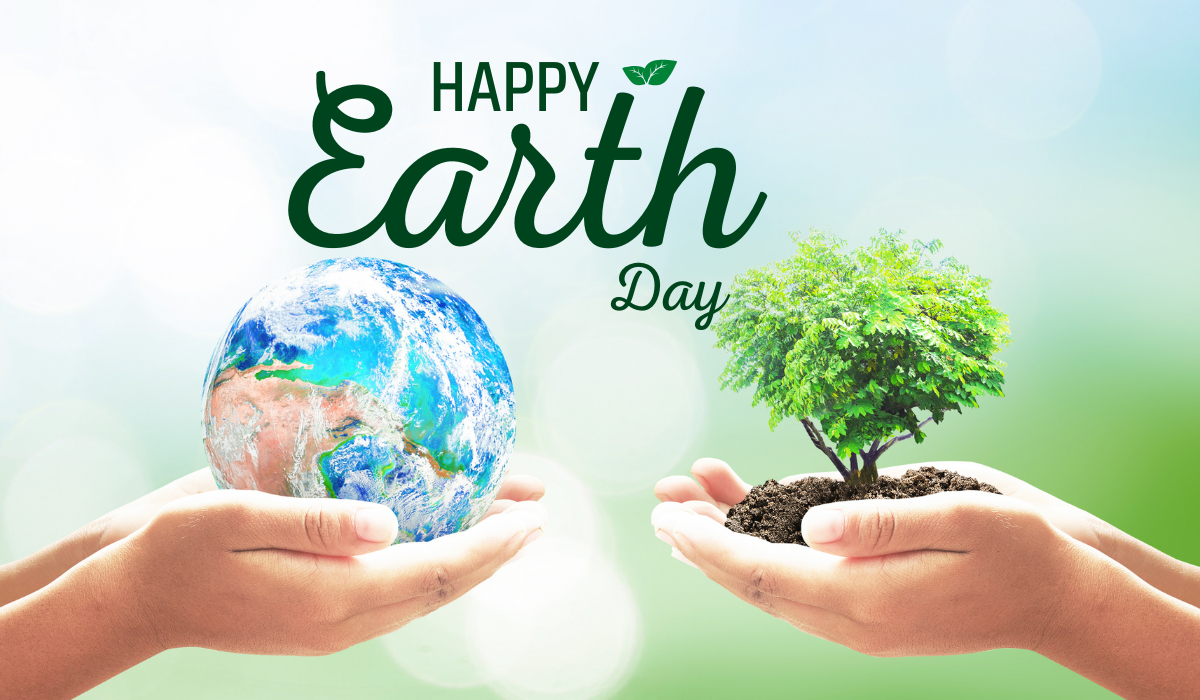 One hand holds a globe and a second hand holds a plant sprout in soil