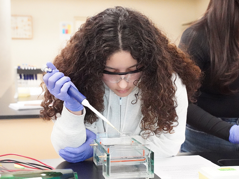 Female biology student pipetting in a lab.