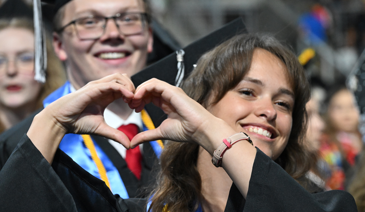 A graduate making a heart with hands.
