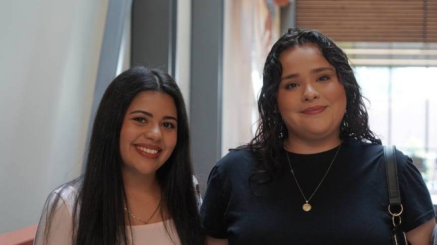 Two students standing near steps inside Mish ee twie