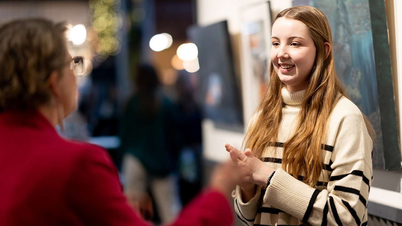 An art student talks with a person at a student art exhibit in Pybus Market.