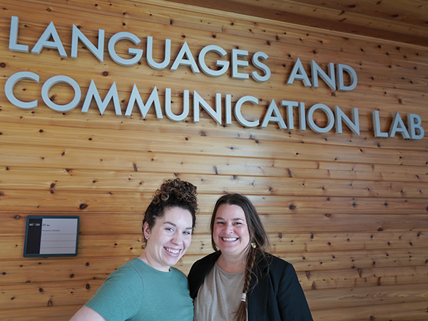 An ASL alum and instructor stand together beneath the Languages and Communication Lab sign.