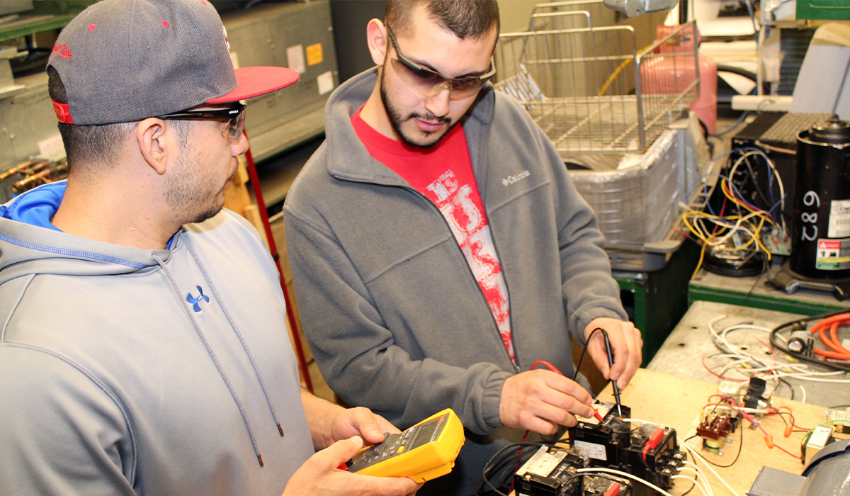 Two students work on electronics equipment.