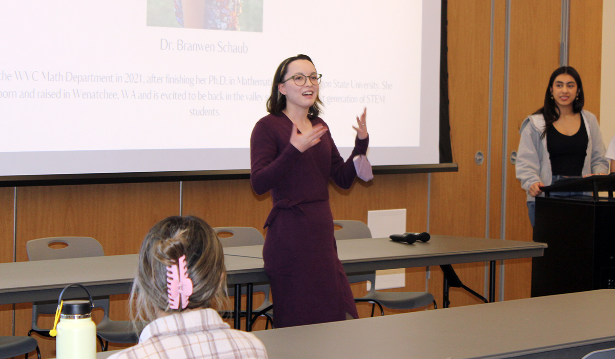 Professor Branwen Schaub stands in front of a screen and gives a presentation to students.
