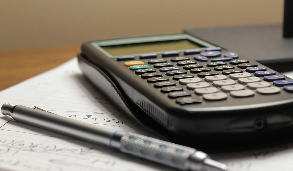 A scientific calculator laying on top of a page of notes.