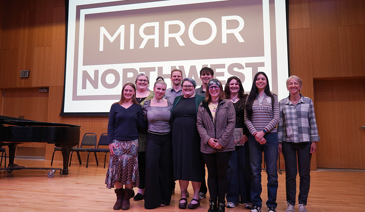 A group of Mirror Northwest writers and editors stand on a stage.