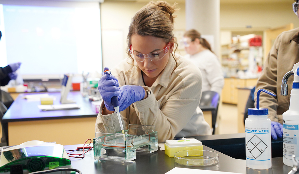 A biology student in a lab conducts an experiment.