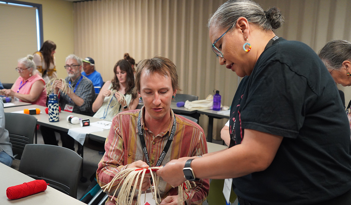Two instructors examine a piece of Native American artwork in a classroom.