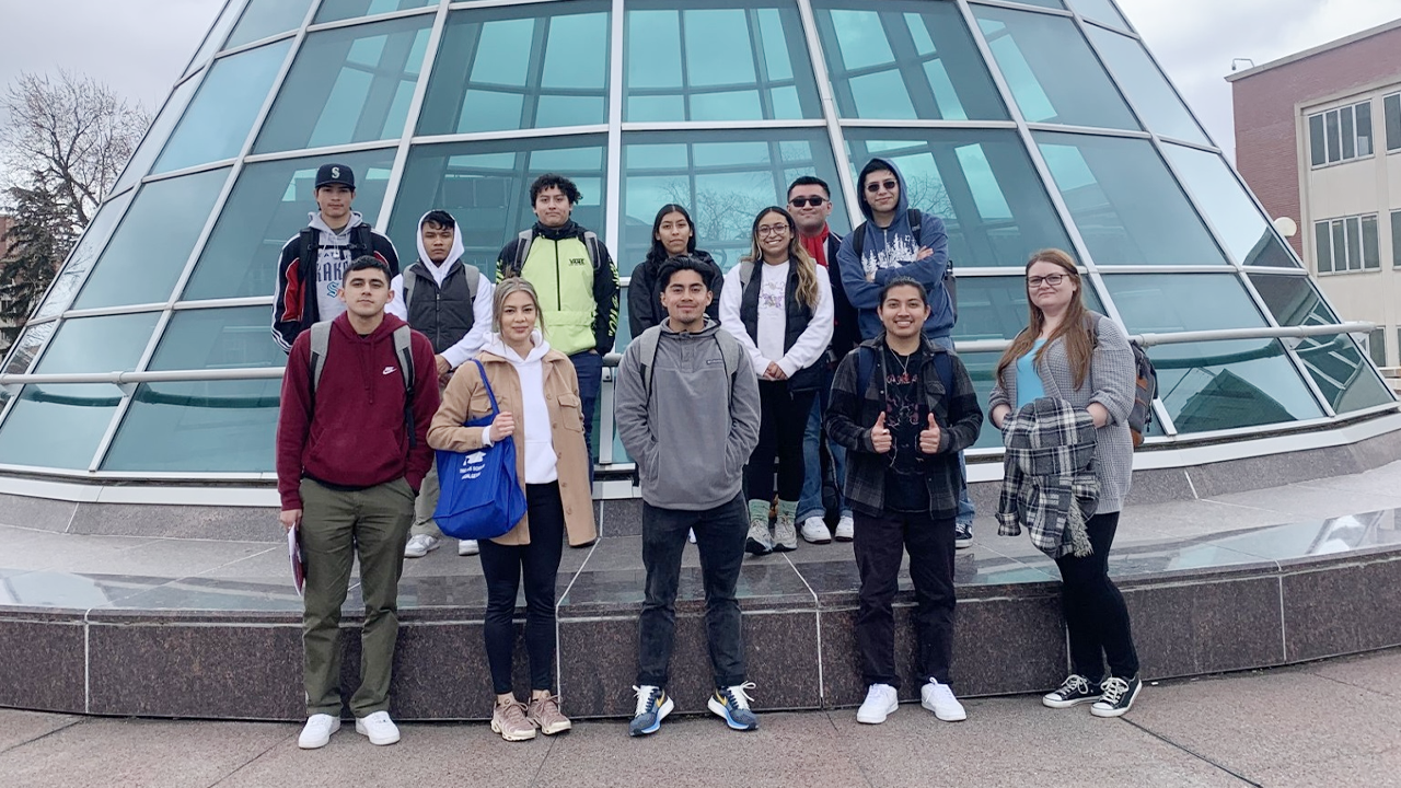 A group of TRIO students stand together near a glass structure.